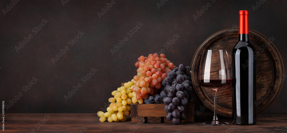 Wine bottle, grapes, glass of red wine and old barrel