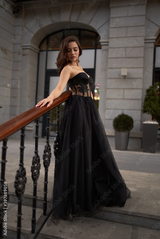 Full-length portrait of an elegant brunette woman with long hair in a black long evening dress. Full-length portrait of an elegant brunette woman with long hair in a black long evening dress.