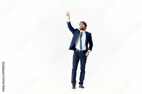 a business man with a beard in a classic suit gestures with his hands on a light background Copy Space