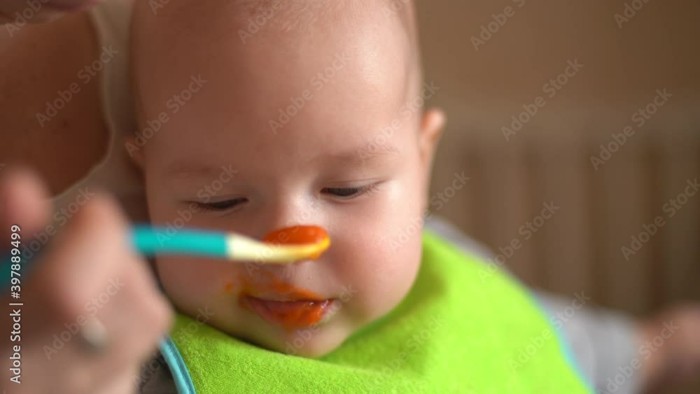 Mother Feeds Baby From Spoon with Pureed Food. Close-up of a Kid Eating Porridge. Mother Feeds Baby From Spoon with Pureed Food. Close-up of a Kid Eating Porridge.