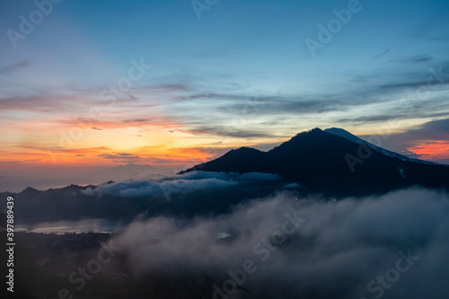 A tropical landscape of cloud movement during the morning sunrise with golden sunbeam behind the mountain in Bali