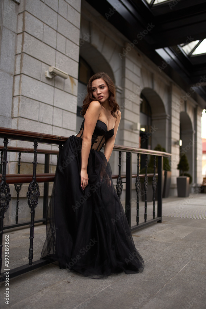 Full-length portrait of an elegant brunette woman with long hair in a black long evening dress. Full-length portrait of an elegant brunette woman with long hair in a black long evening dress.