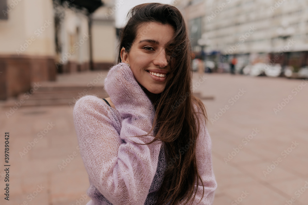 Close up portrait of dreamy shy woman wearing pink shirt touching her cheek and smiling at camera Close up portrait of dreamy shy woman wearing pink shirt touching her cheek and smiling at camera