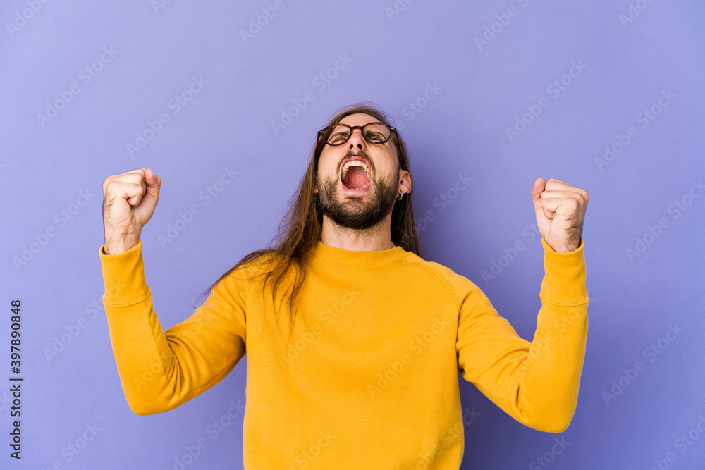 Young man with long hair look raising fist after a victory, winner concept. Young man with long hair look raising fist after a victory, winner concept.