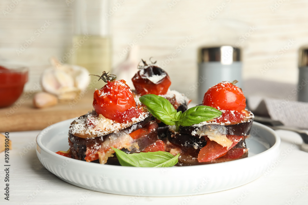 Baked eggplant with tomatoes, cheese and basil served on white wooden table Baked eggplant with tomatoes, cheese and basil served on white wooden table