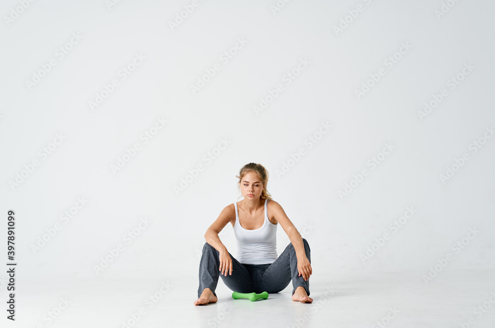 woman in sportswear sitting on the floor indoors and holding dumbbells woman in sportswear sitting on the floor indoors and holding dumbbells