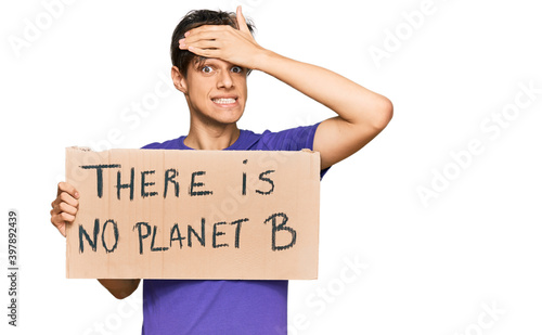 Young hispanic man holding there is no planet b banner stressed and frustrated with hand on head, surprised and angry face © Krakenimages.com