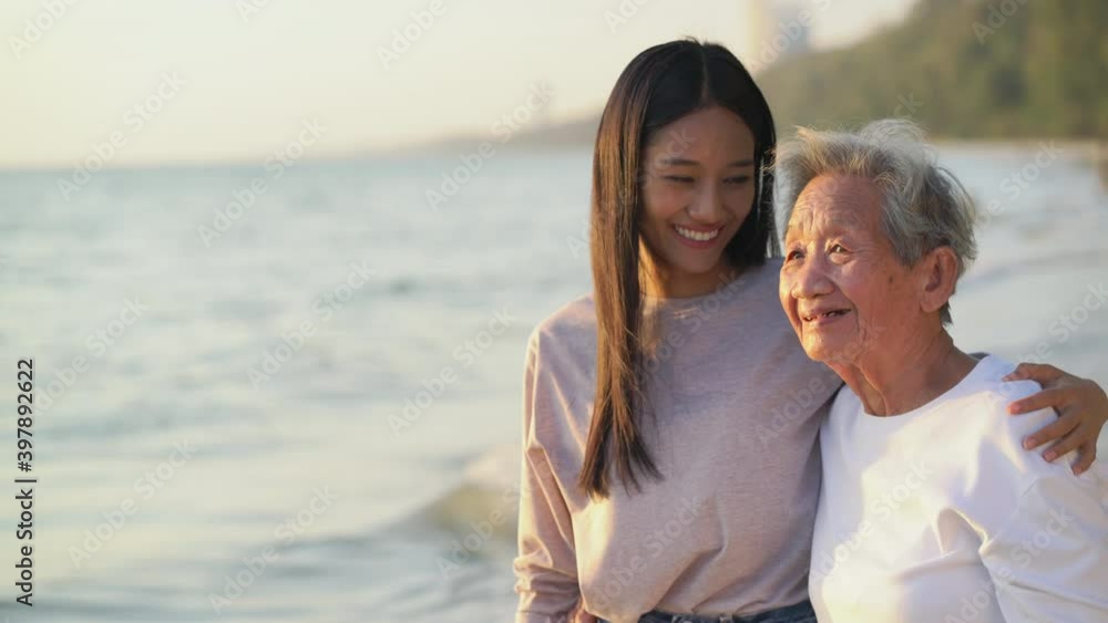 The daughter and grandmother watched the sunset on the beach together The daughter and grandmother watched the sunset on the beach together