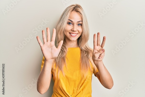 Wallpaper Mural Beautiful caucasian blonde girl wearing casual tshirt showing and pointing up with fingers number eight while smiling confident and happy. Torontodigital.ca