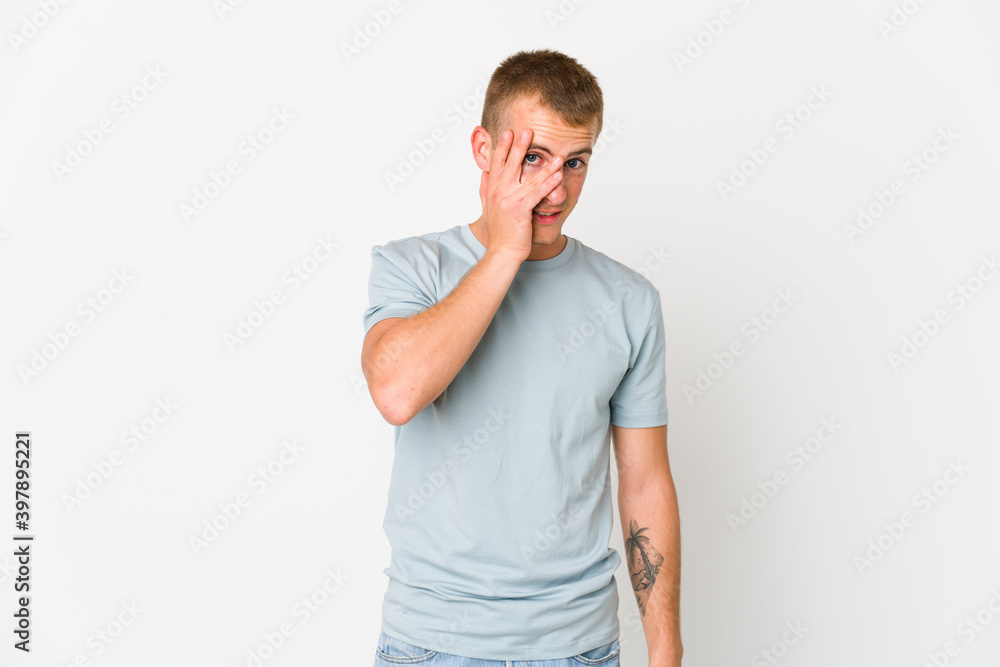 Young caucasian handsome man blink at the camera through fingers, embarrassed covering face. Young caucasian handsome man blink at the camera through fingers, embarrassed covering face.