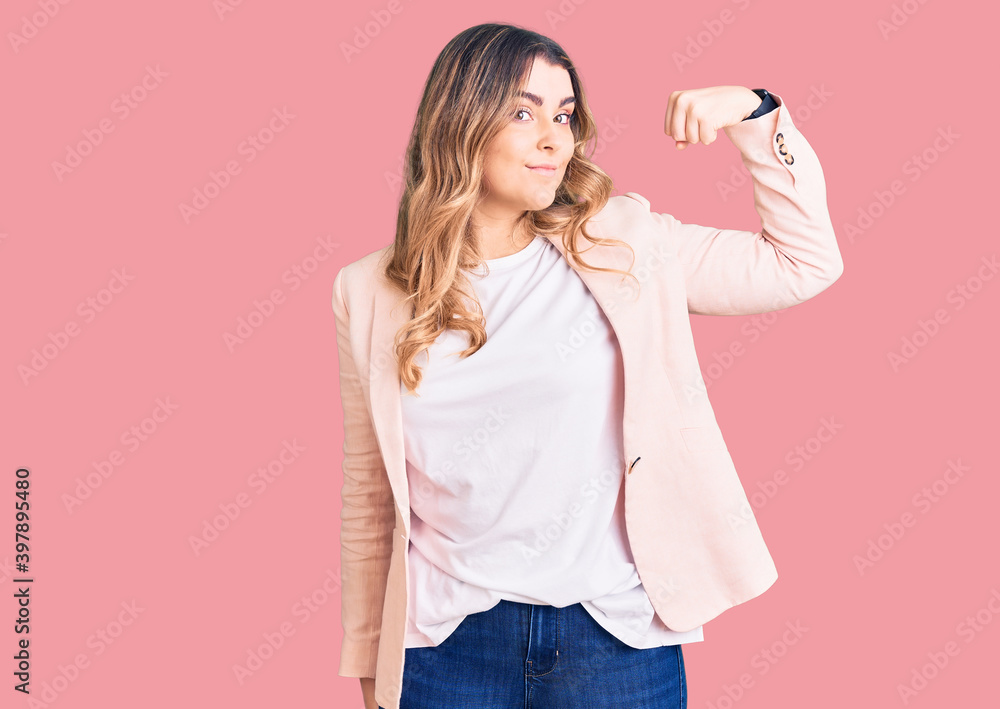 Young caucasian woman wearing business clothes strong person showing arm muscle, confident and proud of power Young caucasian woman wearing business clothes strong person showing arm muscle, confident and proud of power