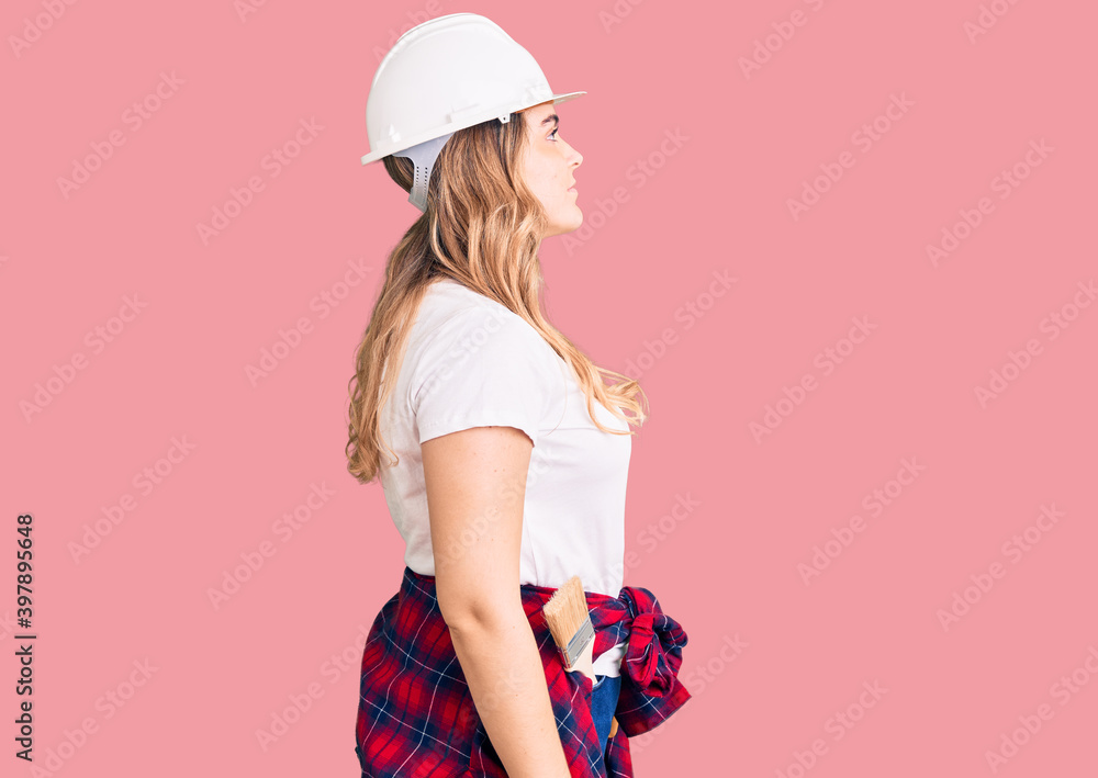 Young caucasian woman wearing security helmet looking to side, relax profile pose with natural face with confident smile. Young caucasian woman wearing security helmet looking to side, relax profile pose with natural face with confident smile.