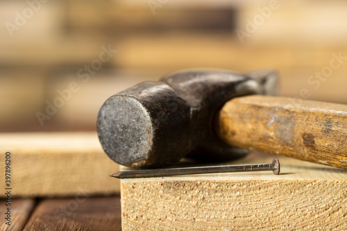 Old hammer and nail on wooden plank, carpenter's tools