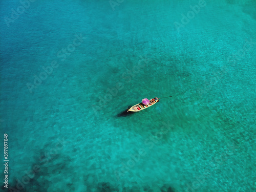 A lonely boat is floating peacefully in the middle of a vast blue ocean, aerial view