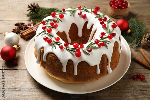 Traditional Christmas cake with cranberries, pomegranate seeds and rosemary on wooden table