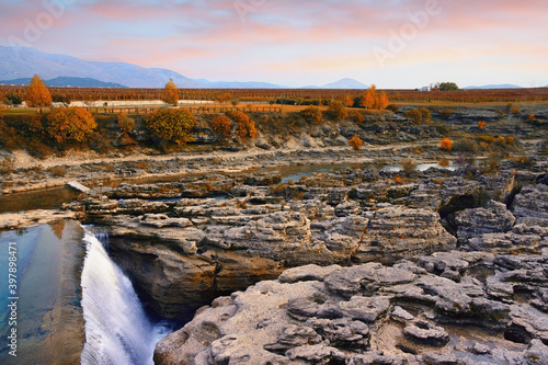 Autumn landscape at sunset. Mountain valley with river, field and vineyard. Montenegro, Podgorica. View of Cijevna river waterfall photo