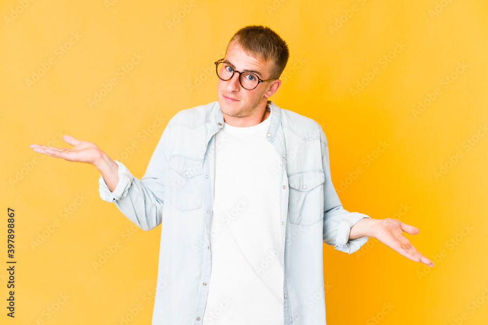 Young caucasian handsome man confused and doubtful shrugging shoulders to hold a copy space. Young caucasian handsome man confused and doubtful shrugging shoulders to hold a copy space.