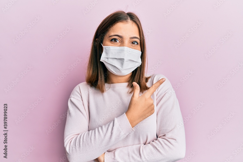 Young beautiful woman wearing medical mask smiling cheerful pointing with hand and finger up to the side Young beautiful woman wearing medical mask smiling cheerful pointing with hand and finger up to the side