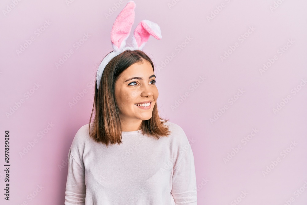 Young beautiful woman wearing cute easter bunny ears looking away to side with smile on face, natural expression. laughing confident. Young beautiful woman wearing cute easter bunny ears looking away to side with smile on face, natural expression. laughing confident.