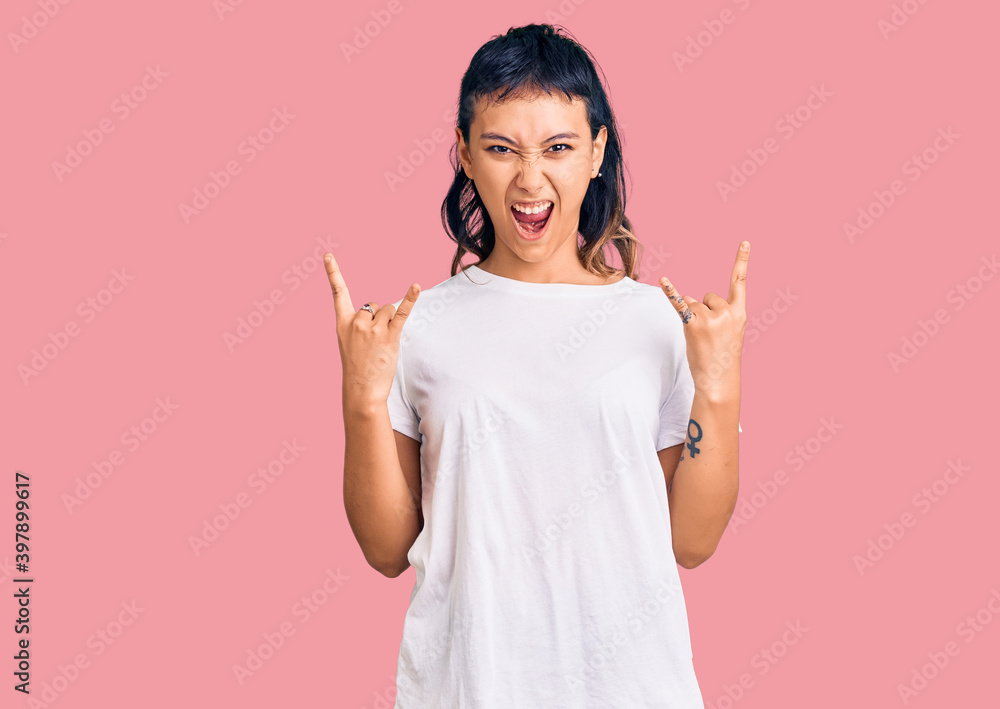 Young woman wearing casual clothes shouting with crazy expression doing rock symbol with hands up. music star. heavy concept. Young woman wearing casual clothes shouting with crazy expression doing rock symbol with hands up. music star. heavy concept.