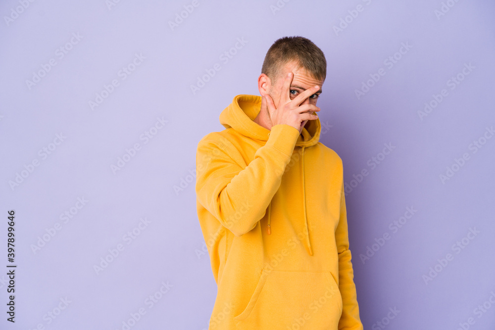 Young caucasian handsome man blink at the camera through fingers, embarrassed covering face. Young caucasian handsome man blink at the camera through fingers, embarrassed covering face.