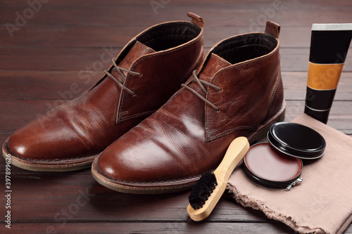 Shoe care accessories and footwear on brown wooden table, closeup