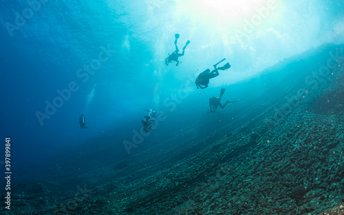Scuba divers underwater in ocean over deep reef in Niihau, Hawaii