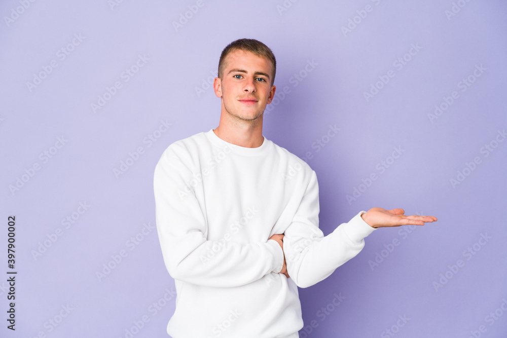 Young caucasian handsome man showing a copy space on a palm and holding another hand on waist. Young caucasian handsome man showing a copy space on a palm and holding another hand on waist.