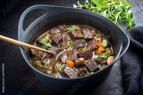 Modern style traditional French boeuf bourguignon with mushrooms and carrots in red wine sauce served as close-up in a Design casserole