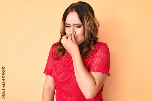 Young beautiful caucasian woman wearing casual clothes smelling something stinky and disgusting, intolerable smell, holding breath with fingers on nose. bad smell