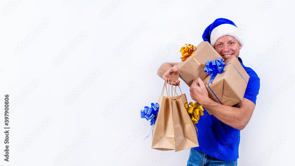 Banner. Happy courier in a blue uniform and Santa hat holds many gifts in his hands. New year and merry Christmas. Man smiles. Secure contactless remote delivery of holiday gifts during coronavirus