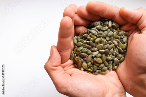 Full hands of peeled pumpkin seeds with white background.