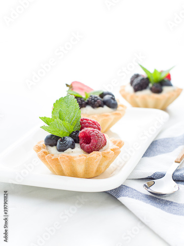 Mini tarts on the plate close up. Homemade dessert with delicious catalonian traditional cream and fresh berries