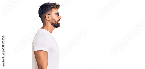 Young hispanic man wearing casual clothes and glasses looking to side, relax profile pose with natural face and confident smile. © Krakenimages.com
