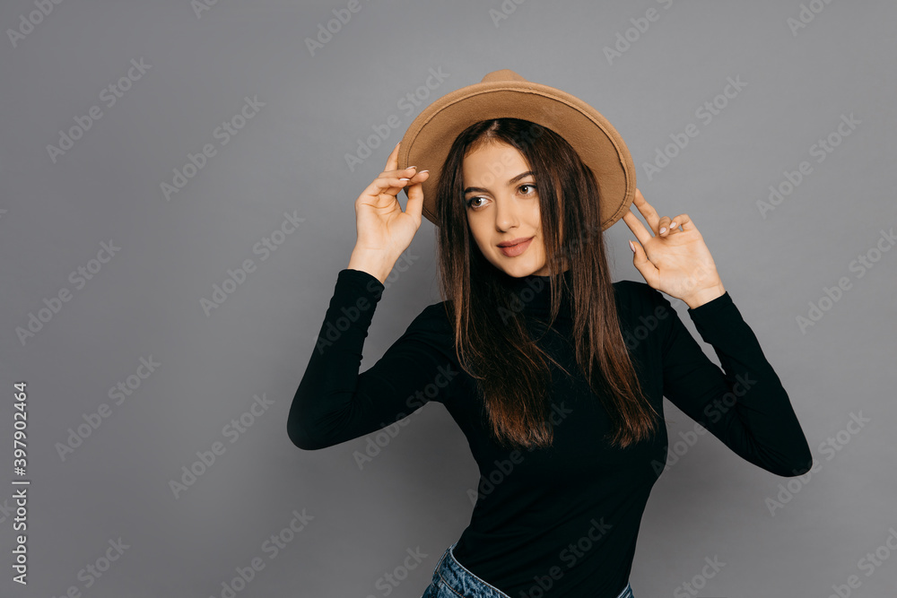 Pretty woman in black t-shirt and yellow hat on gray isolated background Pretty woman in black t-shirt and yellow hat on gray isolated background