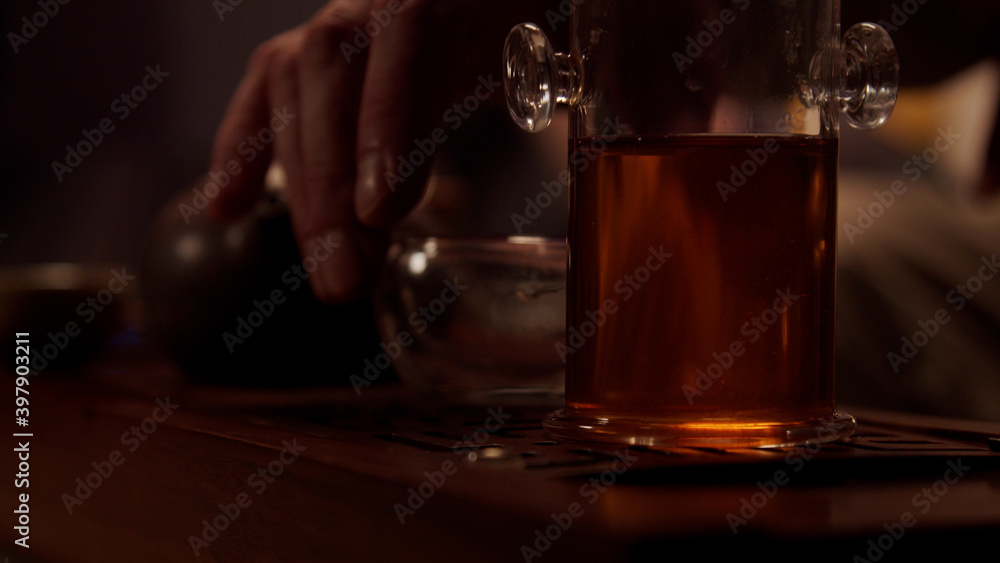 Close-up of a tea seller preparing to hold a tea tasting ceremony in his shop. Places cups, a porcelain teapot, and a tea flask on the chaban.