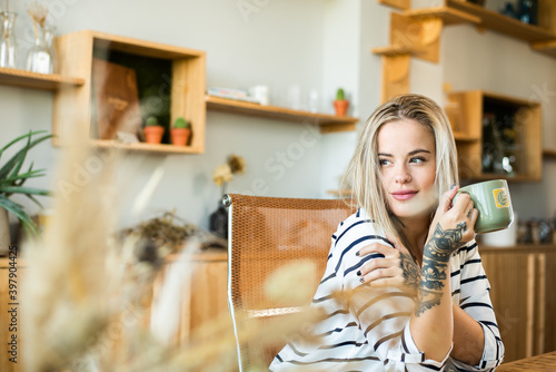 Fotografía Hermosa mujer rubia tomando café mirando hacia una ventana