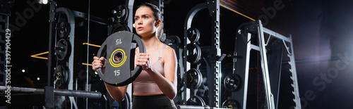 Obraz na plátně athletic sportswoman working out with weight disk in sports center, banner