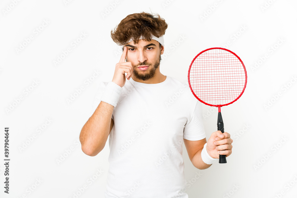 Young indian man playing badminton pointing temple with finger, thinking, focused on a task. Young indian man playing badminton pointing temple with finger, thinking, focused on a task.