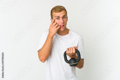 Young caucasian man holding a kettlebell isolated on white background