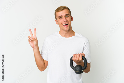 Young caucasian man holding a kettlebell isolated on white background