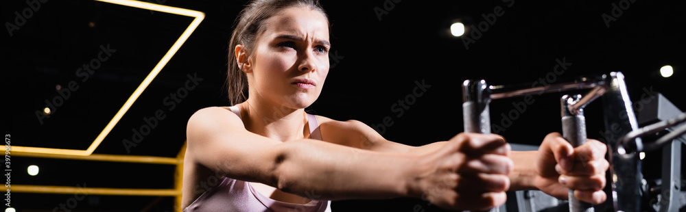 athletic sportswoman exercising on rowing machine on blurred foreground, banner athletic sportswoman exercising on rowing machine on blurred foreground, banner