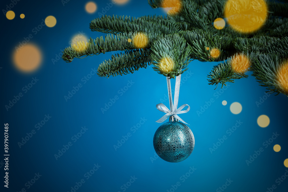 Beautiful Christmas ball hanging on fir tree branch against light blue background, bokeh effect. Space for text