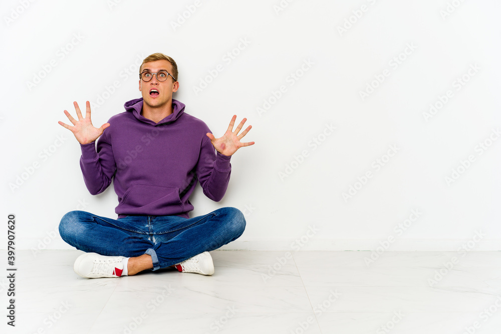 Young caucasian man sitting on the floor screaming to the sky, looking up, frustrated.