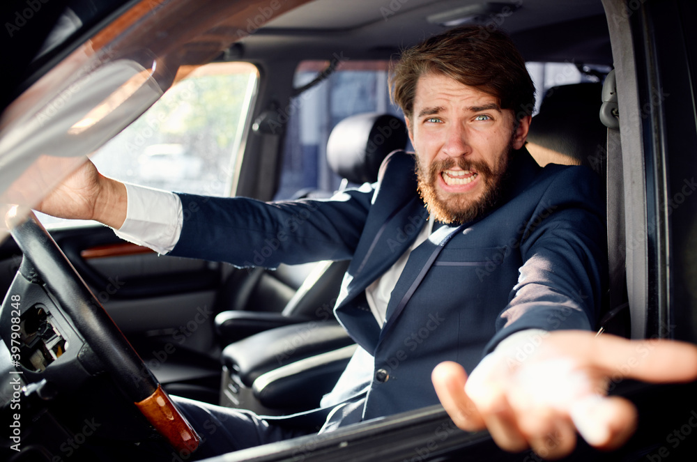 aggressive business man looking out of the car window and gesturing with his hands