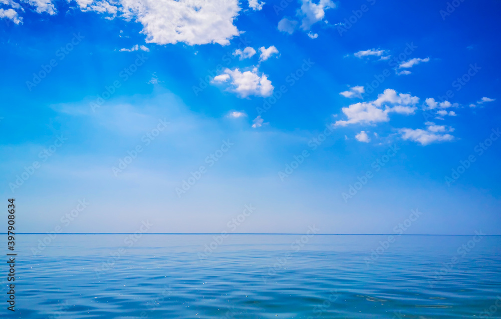 Calm sea and crystal clear sky and straight horizon with some clouds