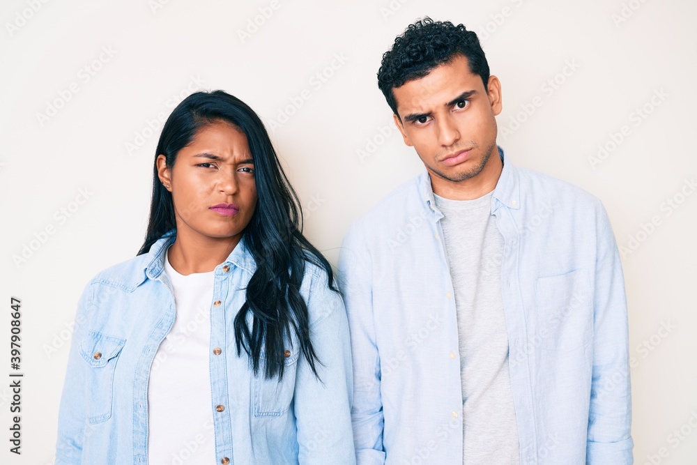 Beautiful latin young couple wearing casual clothes skeptic and nervous, frowning upset because of problem. negative person. Beautiful latin young couple wearing casual clothes skeptic and nervous, frowning upset because of problem. negative person.