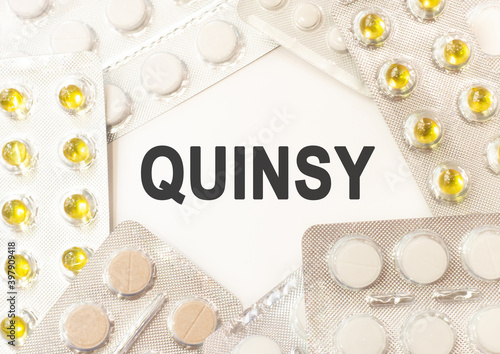 Text quinsy on white background. There are various pills and vitamins around. Medicine concept photo