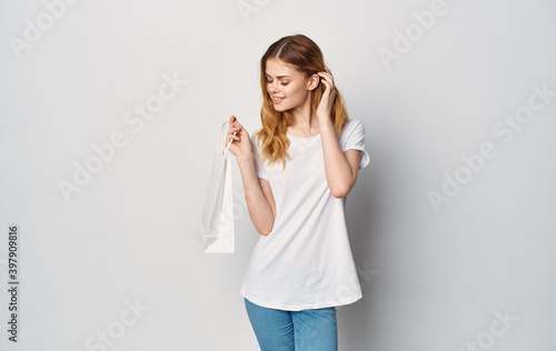 Woman in white t-shirt and jeans package in hands cropped studio view isolated background Shopaholic