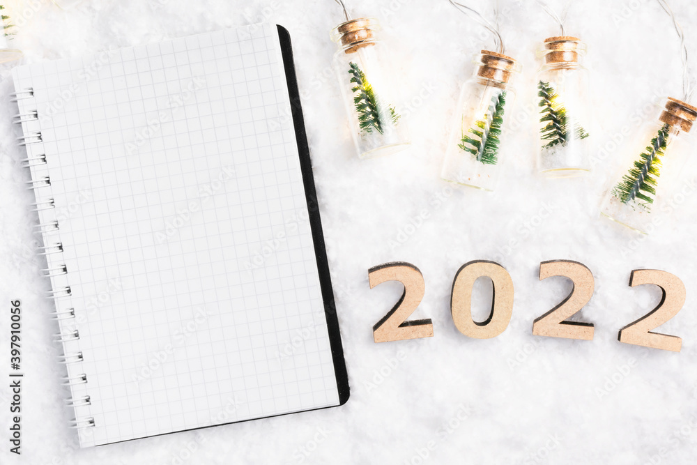 Blank holiday notebook on the snow. Christmas lights and notepad in New Year's style. Blank holiday notebook on the snow. Christmas lights and notepad in New Year's style.